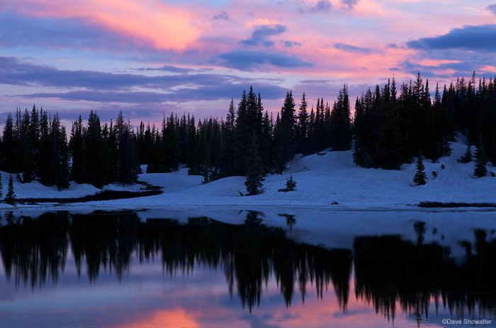 &nbsp;An unnamed tarn reflects sunset light in early July. The forest near timberline still holds a remarkable snowpack well...