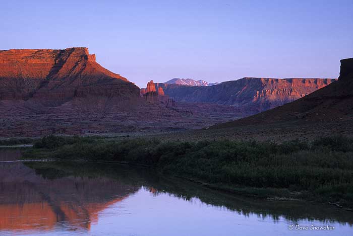 Fisher Towers and the La-Sal Mountains bathe in sunset light over the Colorado River. &nbsp;