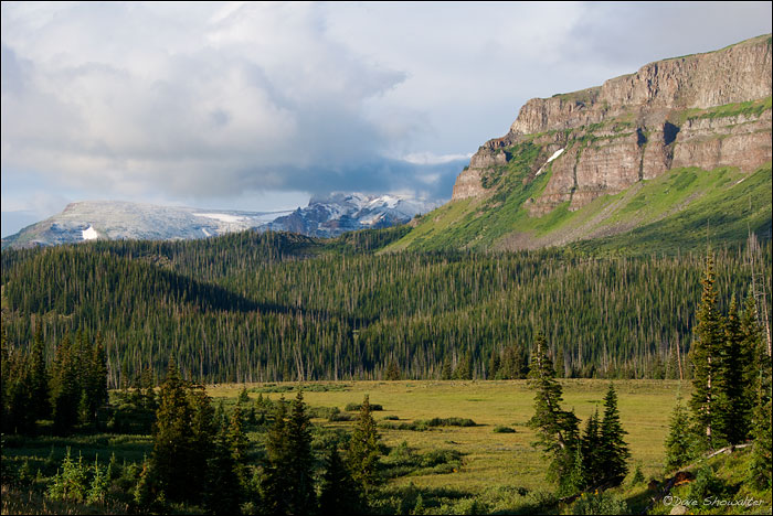 Parting storm clouds reveal fresh summer snow on high peaks ~ contrasted with green meadows in mid-August. Flat Tops Wilderness...