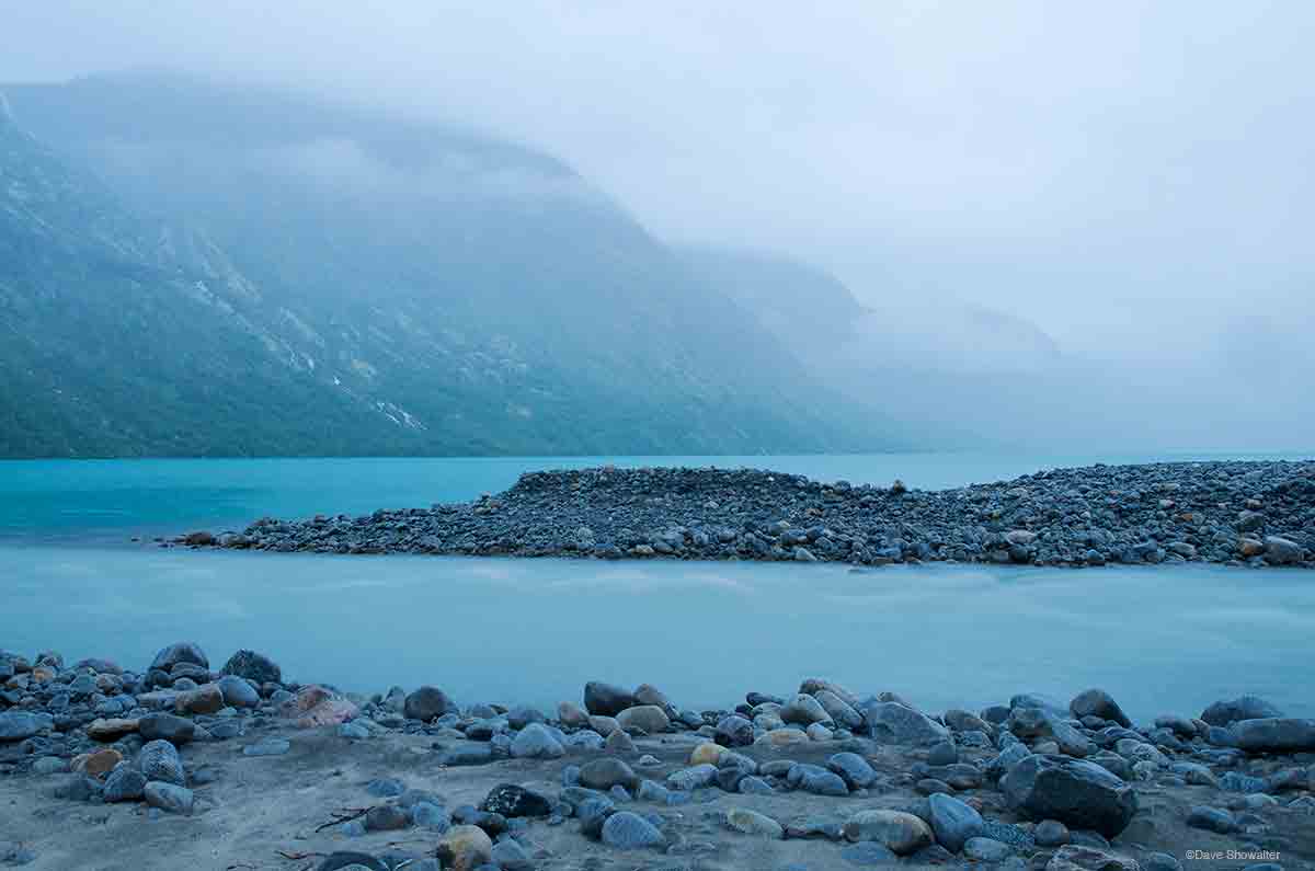 &nbsp;Low clouds and rain make for a moody morning scene along the shores of Gjende Lake. Muru flows from  Austre-Memurubrean...