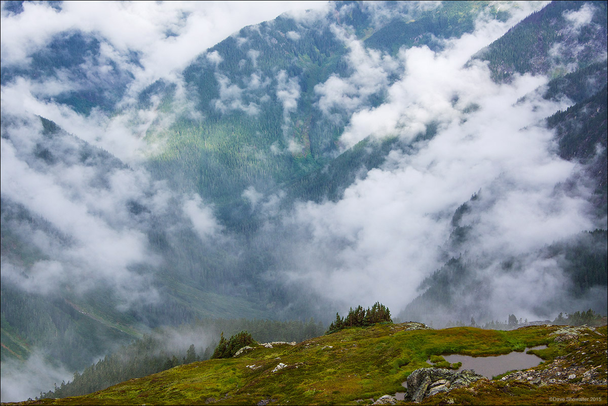 After a long night of heavy rain battering our Sahale Glacier camp, a brief sun break pierces layers of clouds and ridgelines...